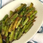 Sautéed Asian Asparagus on a serving plate on a white and blue plaid towel