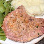 Close up baked pork chop with a curved rib bone on a dinner plate with