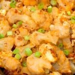 Close up crock pot buffalo cauliflower with buffalo sauce, bacon and green onions