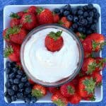 Cheesecake dip for fruit in center of fruit platter on blue napkin