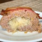 Slice of ground pork and sauerkraut roll topped with a slice of bacon