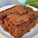 Easy and moist chocolate zucchini cake with chocolate chips on plate with fork