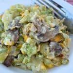 Serving of baked broccoli mushroom casserole on white plate with a fork