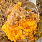 Spoonful of pecan and brown sugar crusted sweet potato casserole over top of a crock pot full