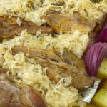 Tender falling about shoulder country ribs nestled in sauerkraut on baking pan