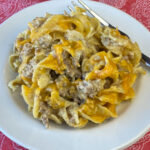 Cheesy and delicious beef and noodle skillet casserole meal on a white plate with a fork