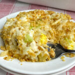 Fork in creamy and hot chicken salad casserole with crunchy celery, water chestnuts and almonds made creamy and flavorful with cream of chicken soup and mayo and topped with buttery baked crackers