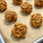 No-bake cookies with peanut butter and cornflakes rolled into balls to set up on parchment paper.