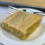 Square piece of Peanut Butter Texas Sheet Cake with a light brown peanut butter frosting and a silver fork in the background.