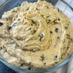 Rich and creamy cottage cheese edible cookie dough heaped up in a glass dish on a blue and white napkin.