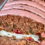 Close up slices of cherry bread with a layer of pink frosting on top.