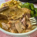 Close up of tender shredded pork falling off of country ribs with a flavorful gravy coating the meat.