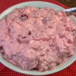 Close up bowl of sweet and creamy cherry fluff salad on a bright red and white napkin.