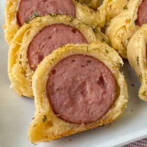 Close up slice of Kielbasa on a roll with a delicious buttery, seasoning baked on top.