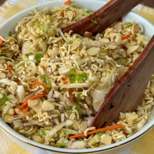 Close up toppings of crunchy noodles, sliced almonds, sunflower seeds and sliced green onions on an Asian ramen noodle salad.