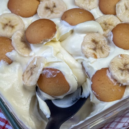 Cool and creamy pan of banana pudding with a spoon scooping from the outside corner.