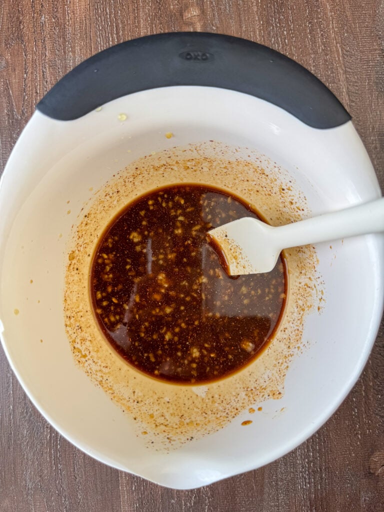 White spatula stirring together an easy Asian marinade in a small mixing bowl.