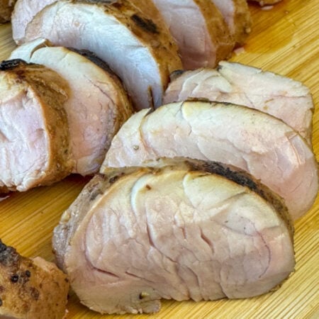 Slices of the most tender cut of pork tenderloin that's been marinaded in simple Asian flavors on a cutting board.