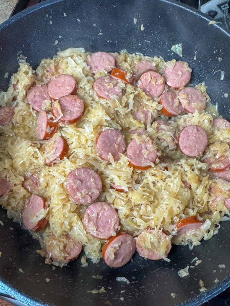 Thick layer of sauerkraut with softened onions stirred into butter with slices of Kielbasa nestled in to cook.