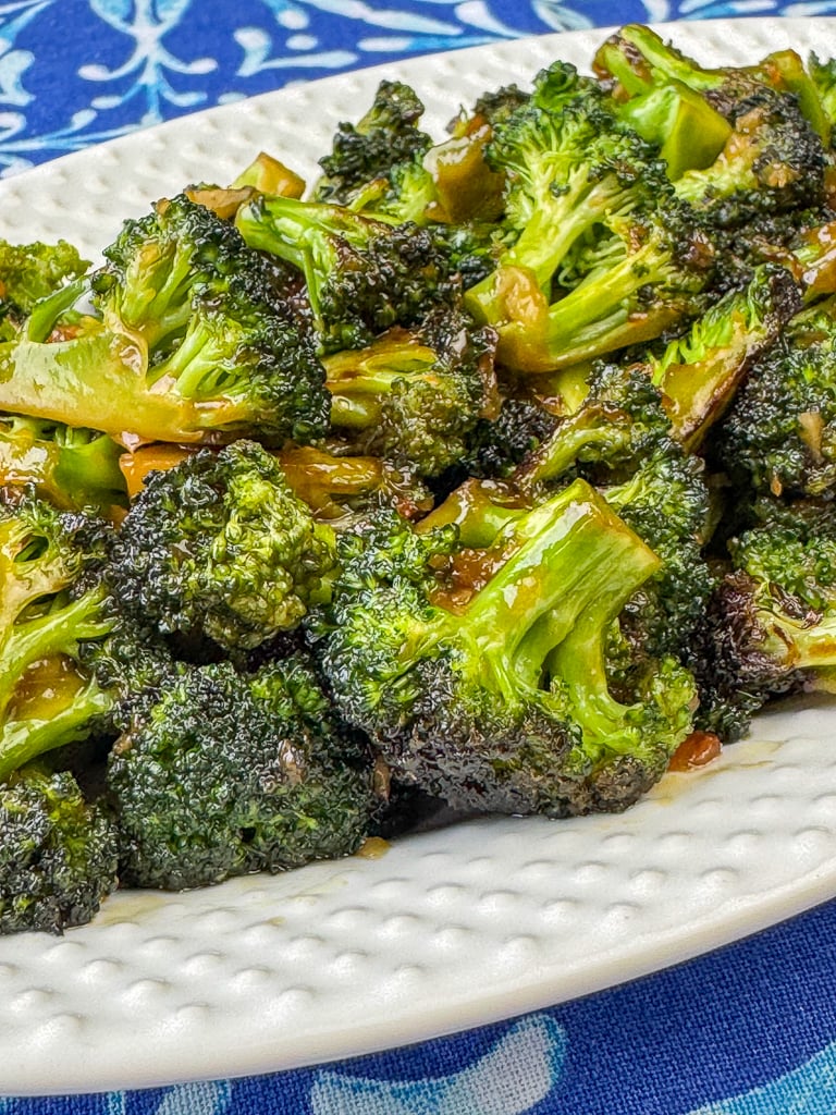 Close up florets of broccoli with a simple and delicious Asian sauce on a white serving plate.