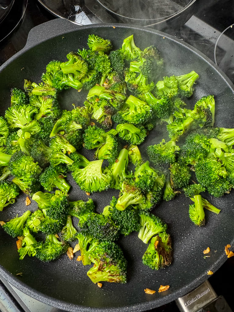 Steam coming off of small bits of broccoli saut&eacute;ing in a skillet.