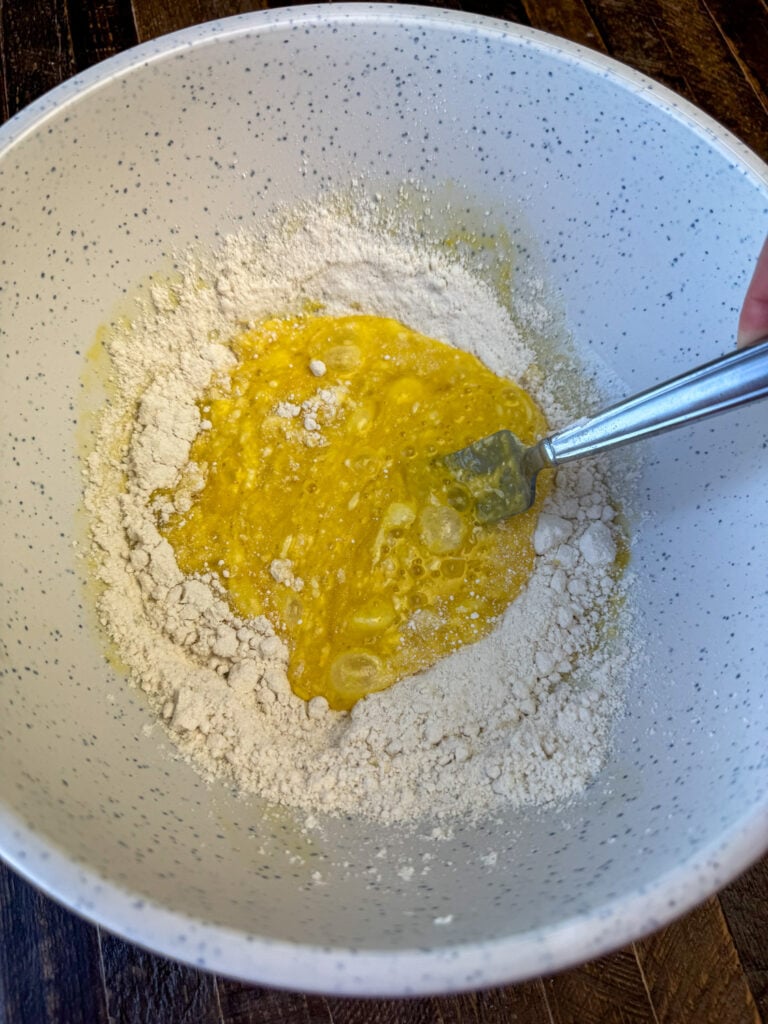 Fork mixing scrambled eggs into a small amount of baking mix.