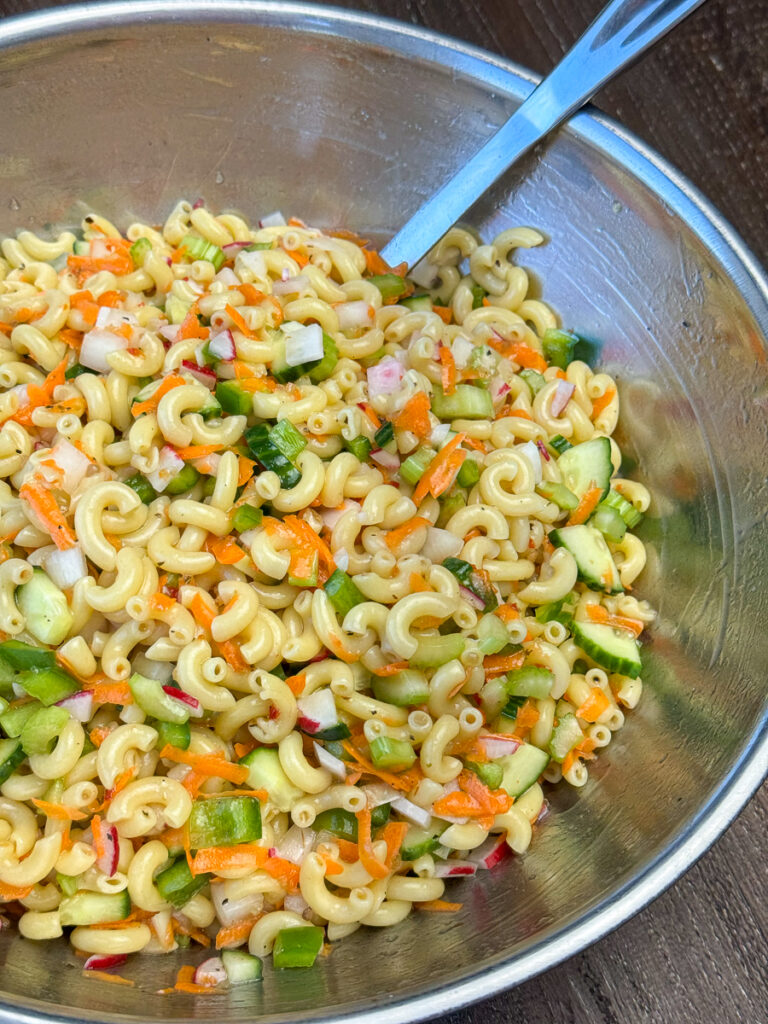 Overhead view of a bowl with a variety of old fashioned vegetables stirred into macaroni with Italian dressing.
