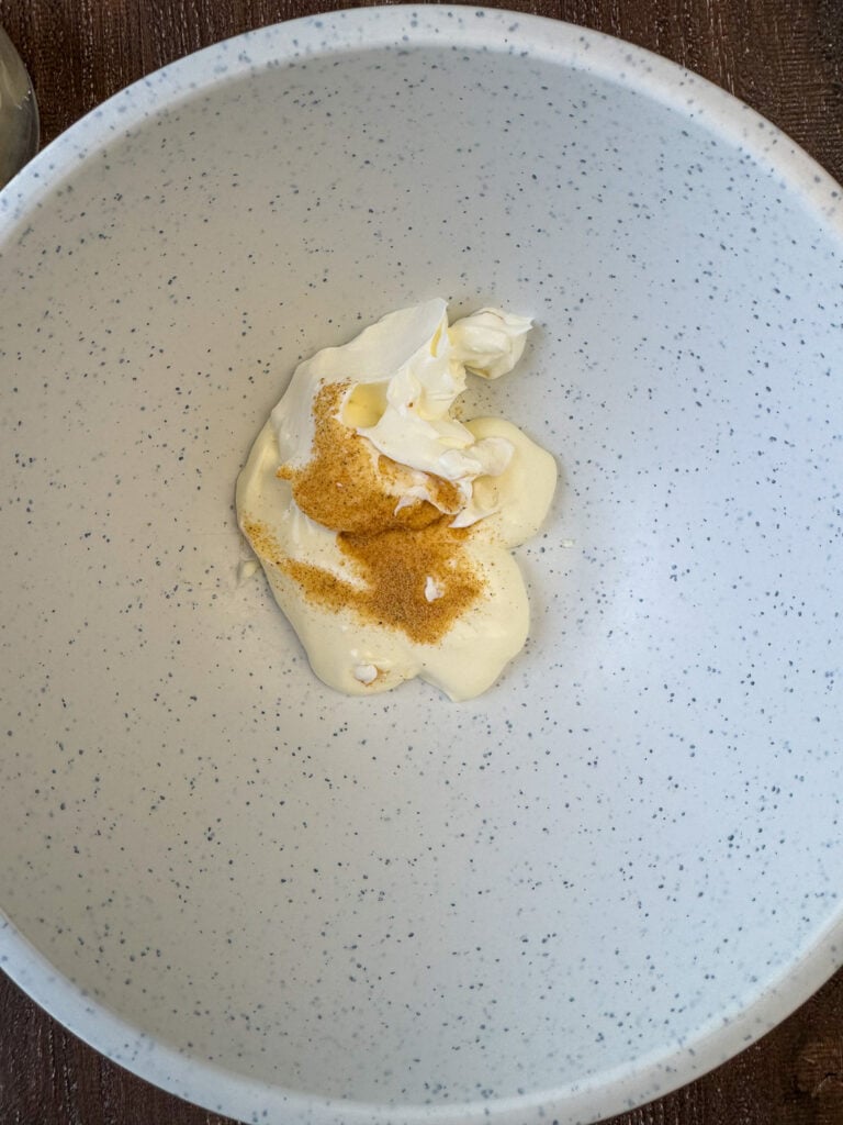 Mayo and sour cream in a mixing bowl with seasoned salt to make a simple salad dressing for peas.