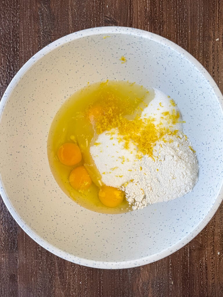 Lemon zest, eggs, granulated sugar and flour in a mixing bowl.