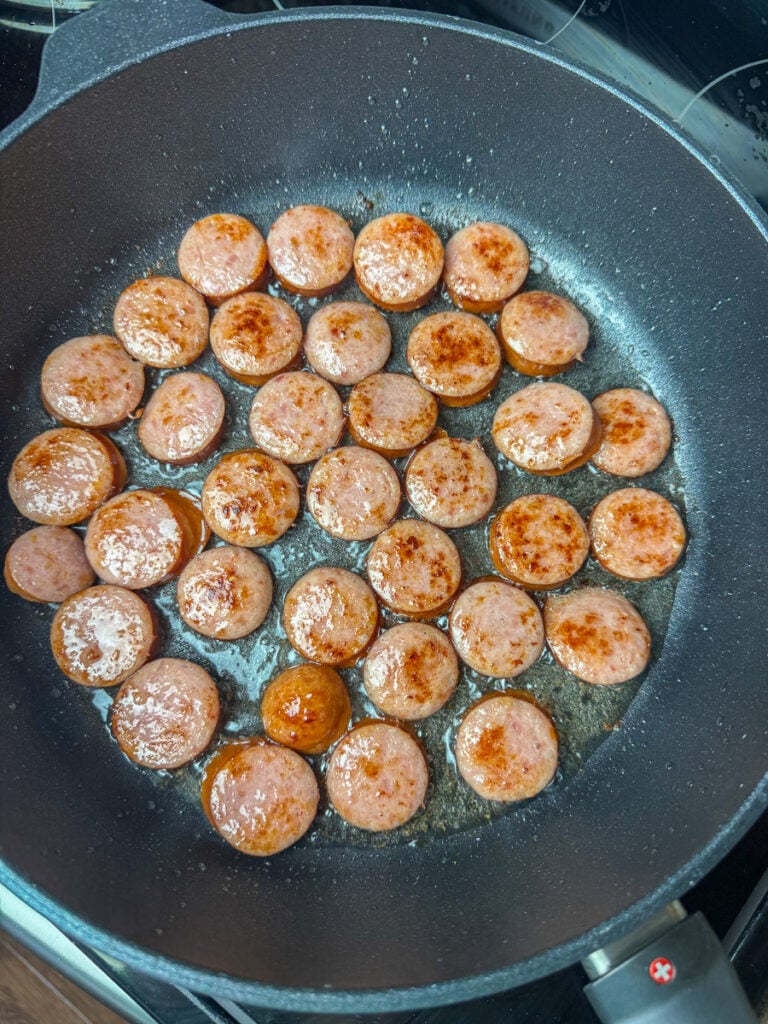 Brown slices of smoked sausage in a non-stick skillet with hot oil.