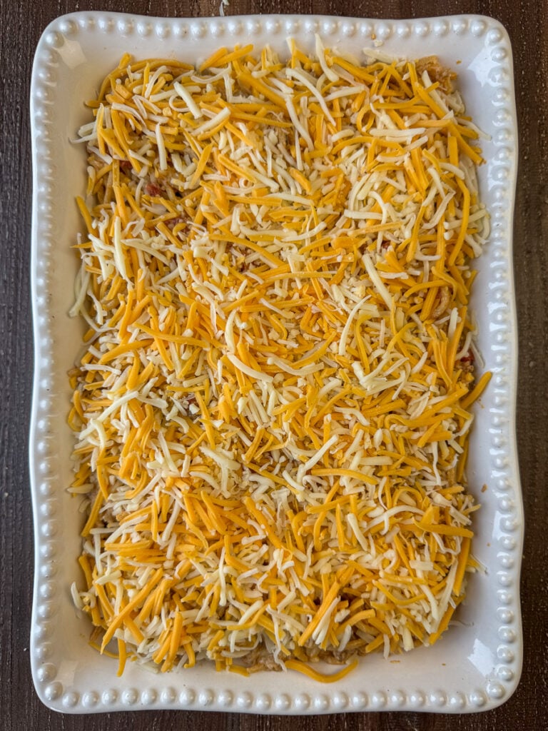 A think layer of shredded Mexican cheese spread over top of a spaghetti taco casserole.