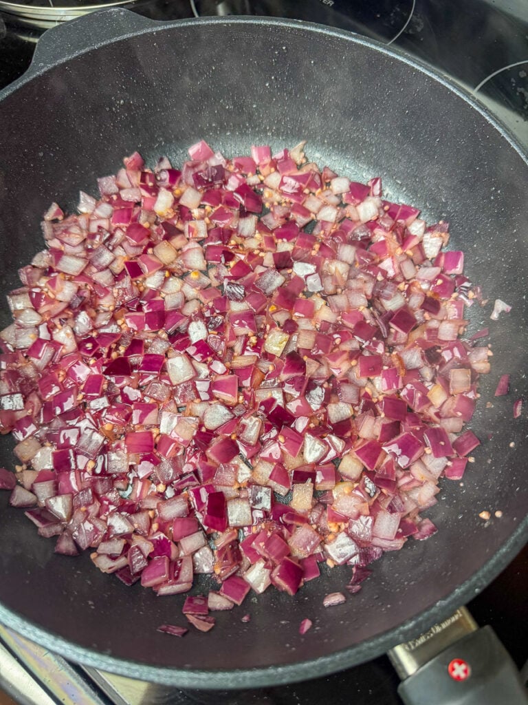 Red onion cooked until tender and infused with garlic flavor in a skillet.