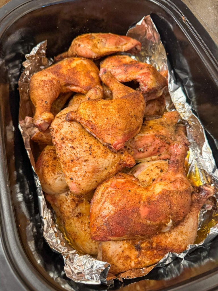 Smoked chicken quarters set to keep warm in a foil lined electric roaster to hold while waiting to serve.