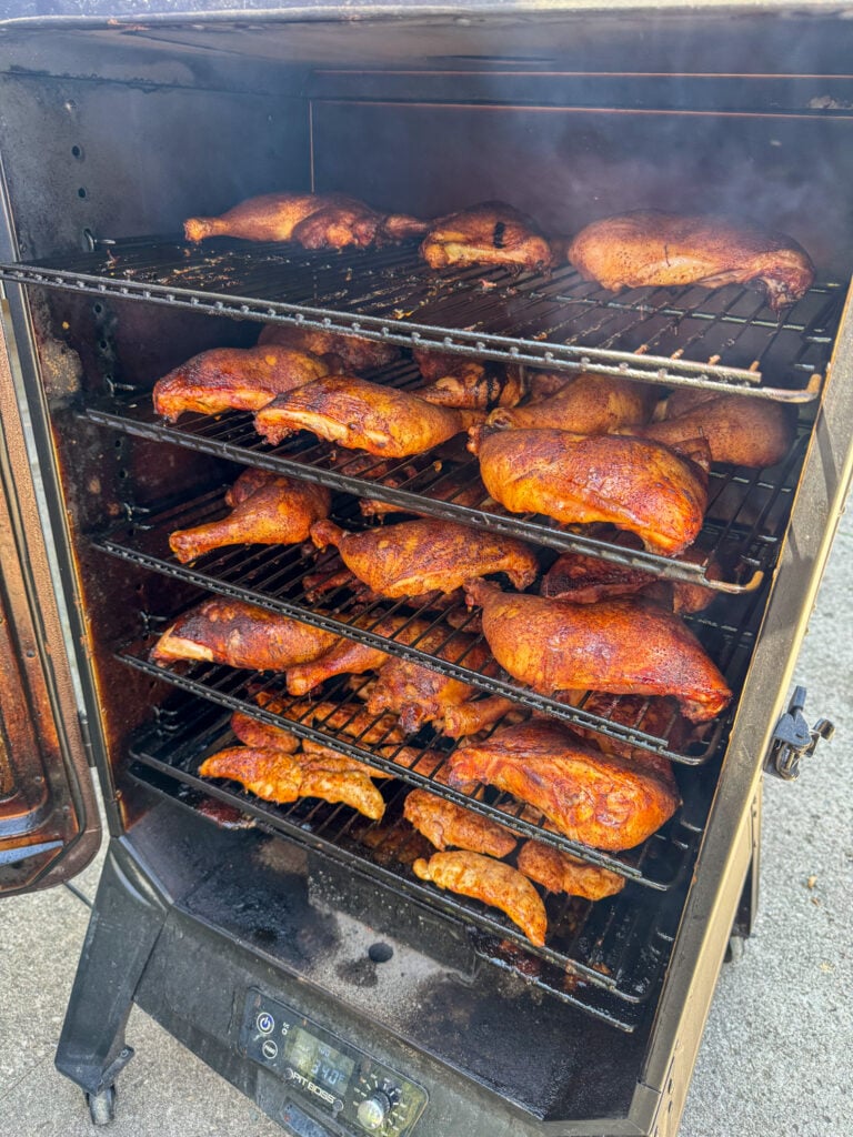 Vertical cabinet smoker full of perfectly cooked chicken quarters for a crowd.