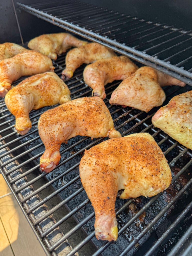 Lightly golden, fully cooked and juicy smoked chicken leg quarters on a Traeger smoker.