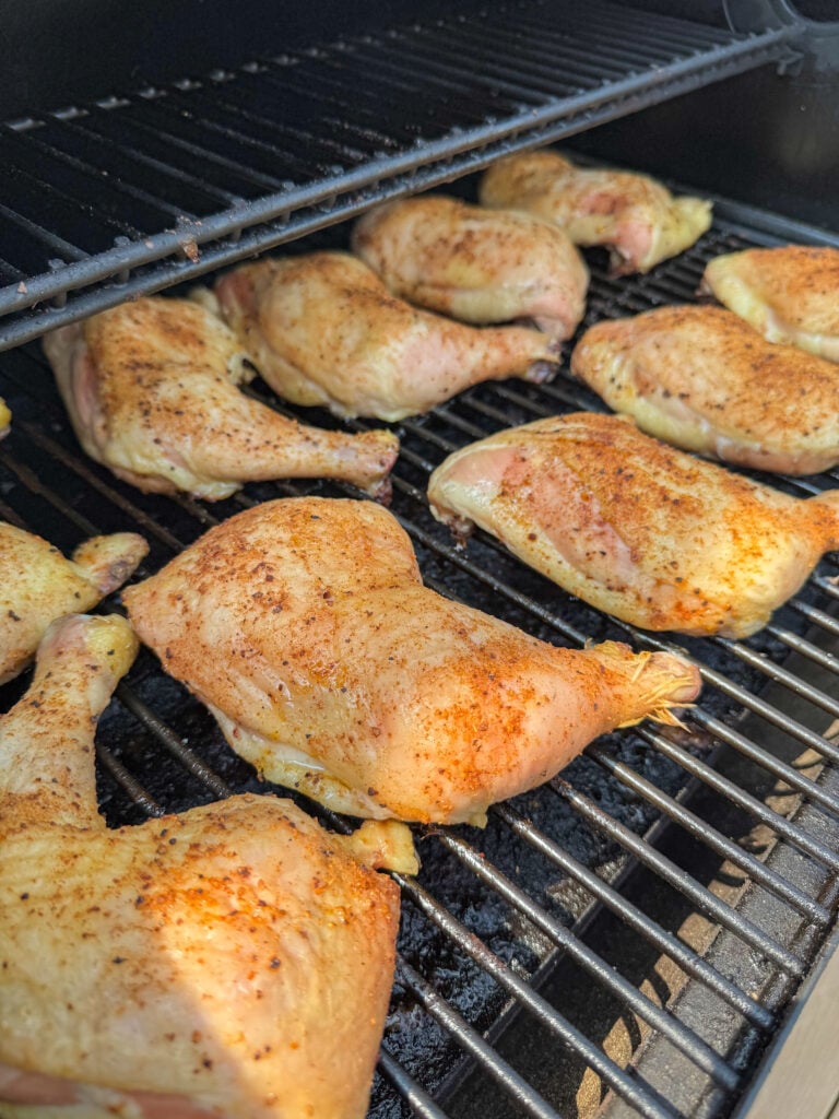 Side view of partially cooked smoked chicken quarters on an electric pellet grill.