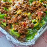 Close up of cooked ground beef with taco seasoning, salsa, and melted cheese on a bed of bell pepper nachos.