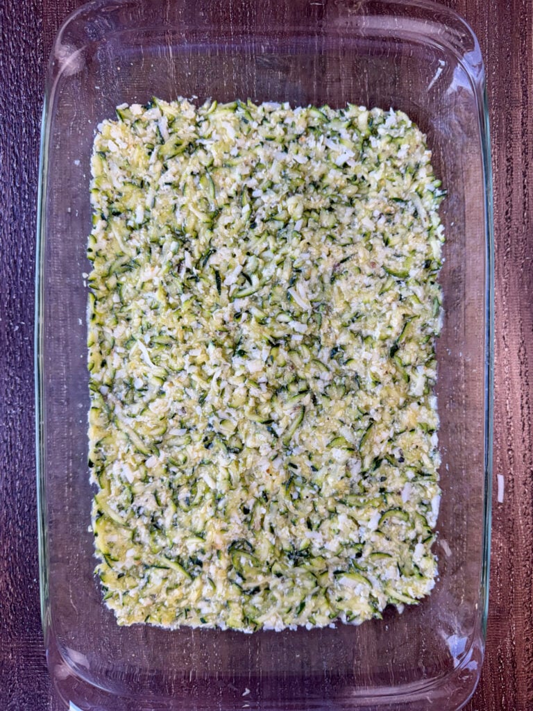 Cheesy zucchini casserole base spread in a 9 x 13" dish.