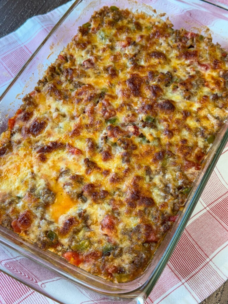 Golden brown cheese baked on a low carb zucchini and casserole recipe in a 13 x 9 pan resting on a red and white plaid napkin.