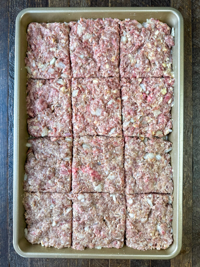 Hamburger pressed flat into a sheet pan and cut into square steaks.