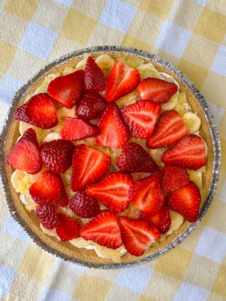 Slices of strawberries on top of crushed pineapple and slices of bananas on a banana split pie recipe.