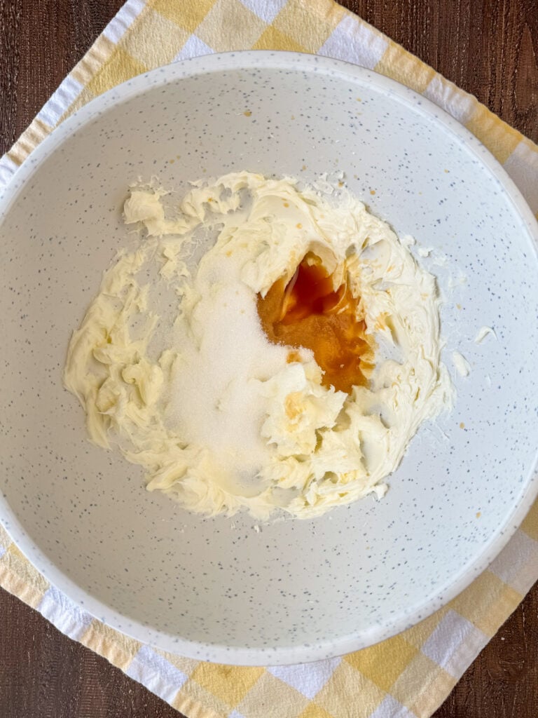 Whipped cream cheese with granulated sugar and vanilla extract added to the mixing bowl.