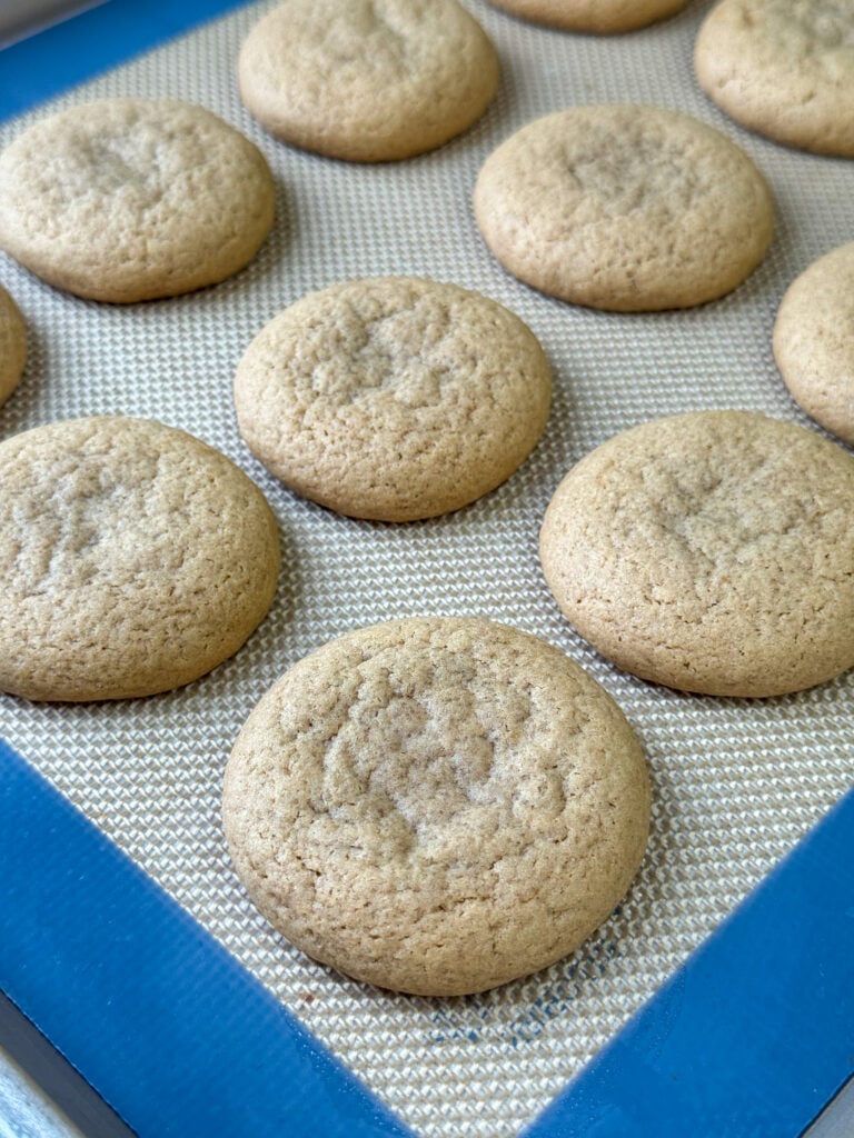 Warm, soft caramel cookies cookies on a baking sheet with a non-stick liner.
