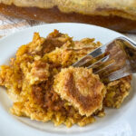 Close up cobbler like texture to a dump pumpkin cake with a fork in.
