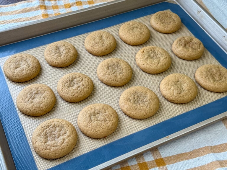 Baking sheet full of soft caramel cookies with a tender crumb resting on a yellow and white napkin.
