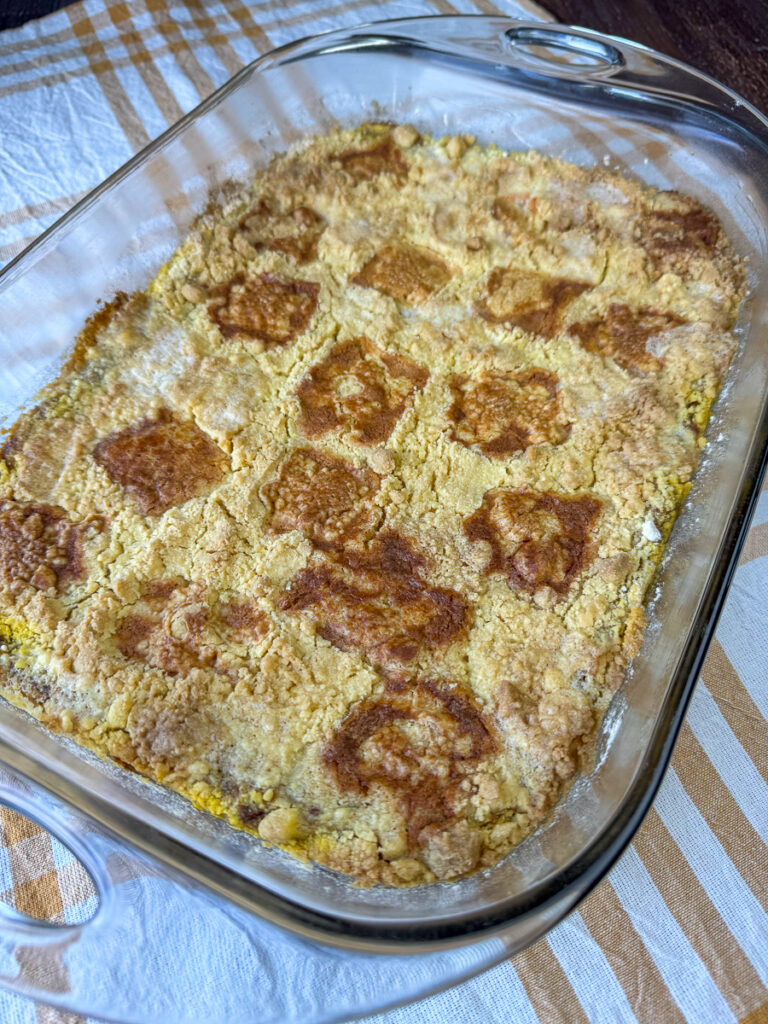 Pats of butter melted and baked on top of a pumpkin dump spice cake resting on a white and yellow napkin.