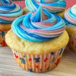 Close up of a moist white cupcake with red, white and blue frosting.