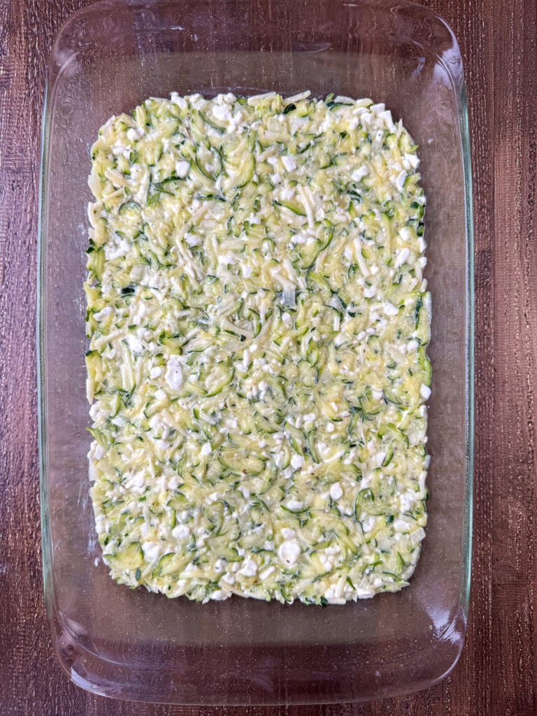 Zucchini and cottage cheese mixture with eggs smoothed into the bottom of a 9 x 13" glass baking dish.
