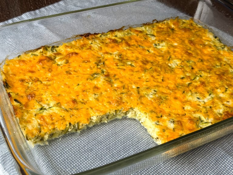 Overhead view of cheddar cheese melted on top of a healthy zucchini casserole on a blue and white napkin.