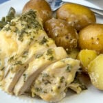 Tender sliced chicken breast coated with a cream of chicken soup based sauce flavored with parmesan cheese and garlic with some sauce spooned over baby potatoes on the back of the plate.